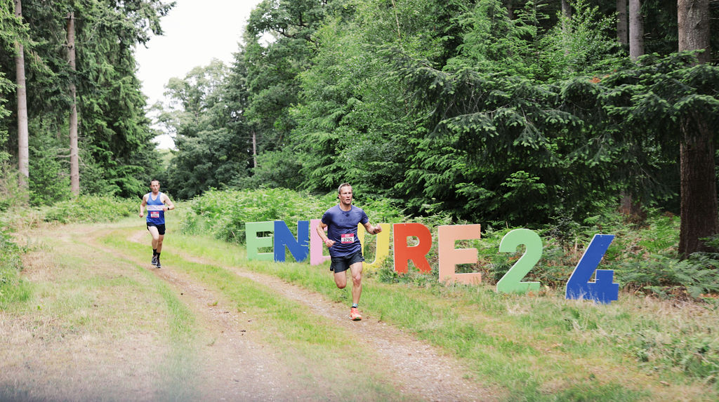 Trekkers running past the Endure 24 logo